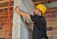 Elektryk w kasku montuje instalację w powstającym domu pasywnym