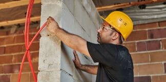 Elektryk w kasku montuje instalację w powstającym domu pasywnym