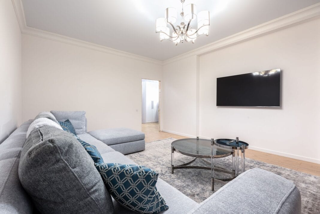 Nowoczesny salon z telewizorem na ścianie, sofą i żyrandolem Nowoczesny salon z telewizorem na ścianie, sofą i żyrandolem
