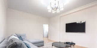 Nowoczesny salon z telewizorem na ścianie, sofą i żyrandolem