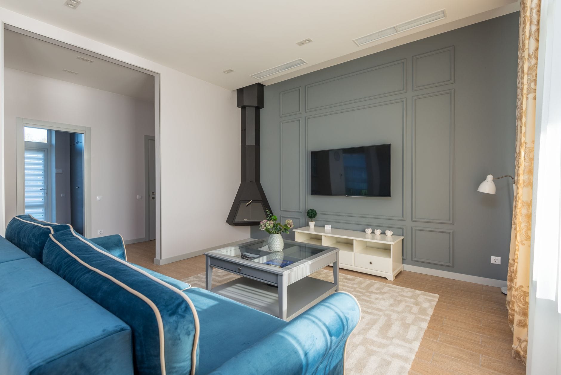 Salon z niebieską sofą i ścianą TV z elegancką aranżacją